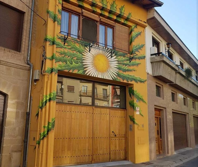 Pintura de fachada en una vivienda individiual. Un símbolo tradicional del sol representado en una planta y después plasmado en una pared con un marcado tono realista.